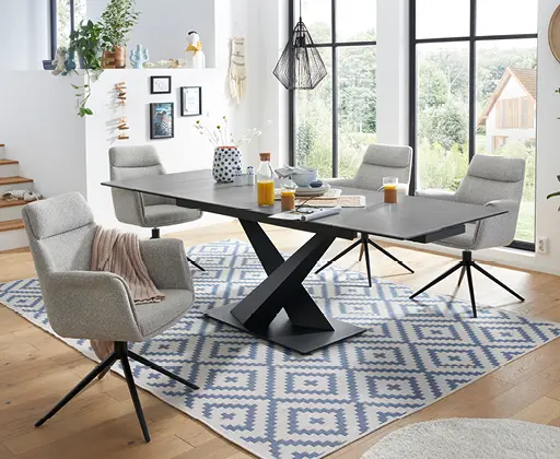 Moderner Essbereich mit schwarzem Tisch, grauen Polsterstühlen und geometrischem Teppich.